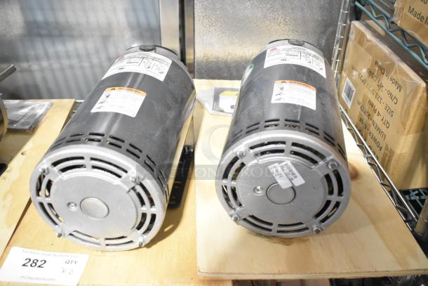 2 US Motors FK75 condenser fan motors, 208-230/460 volts, 3 phase, with labels detailing specifications and warnings.
