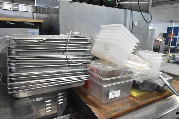 Lot of stainless steel and poly drop-in bins, varying sizes, stacked. Includes full-size stainless bins, plastic lids.