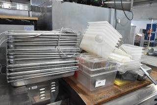 Lot of stainless steel and poly drop-in bins, varying sizes, stacked. Includes full-size stainless bins, plastic lids.