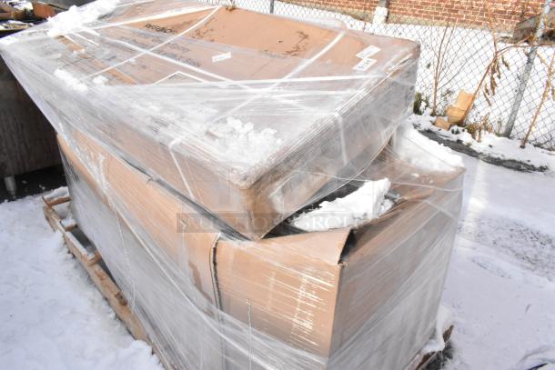 Boxes containing scratch and dent items, including a 460EG2460DR3 shelf and stainless steel sink, wrapped in plastic and snow.