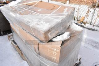 Boxes containing scratch and dent items, including a 460EG2460DR3 shelf and stainless steel sink, wrapped in plastic and snow.