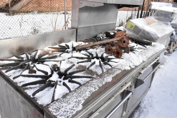 Wolf stainless steel 10 burner range with salamander, cheese melter, and 2 ovens, snow-covered, used condition.