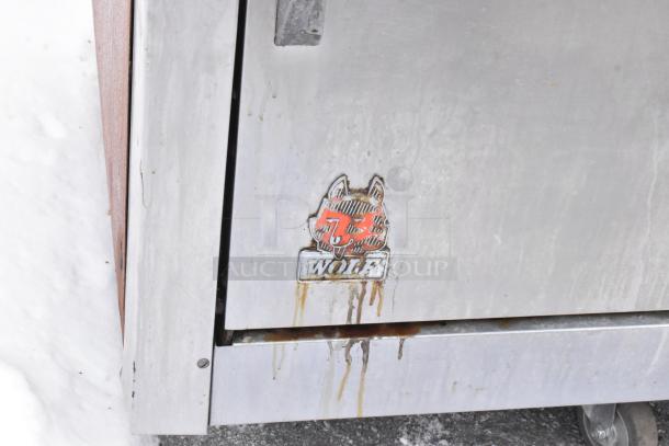 Wolf stainless steel commercial gas range, featuring 10 burners, salamander cheese melter, and 2 ovens. Visible Wolf logo.