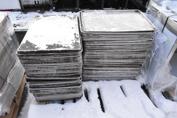 108 metal full-size baking pans in stacked rows, showing signs of wear. Auction lot includes 108 pans per bid.