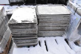 108 metal full-size baking pans in stacked rows, showing signs of wear. Auction lot includes 108 pans per bid.