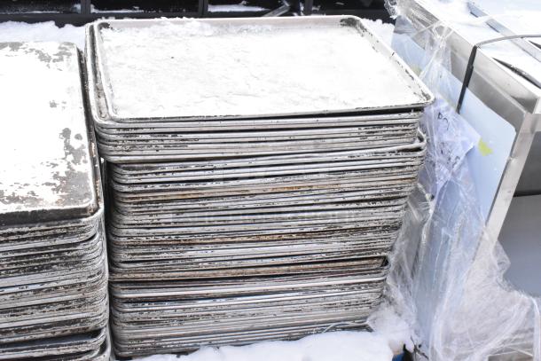 Stack of full-size metal baking pans, 108 in total, showing visible signs of heavy use and wear.