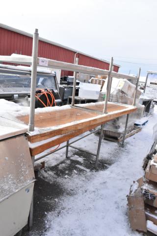 Two wooden butcher block tables, one with an under shelf. Steel frame, used condition, snow-covered, auction label visible.