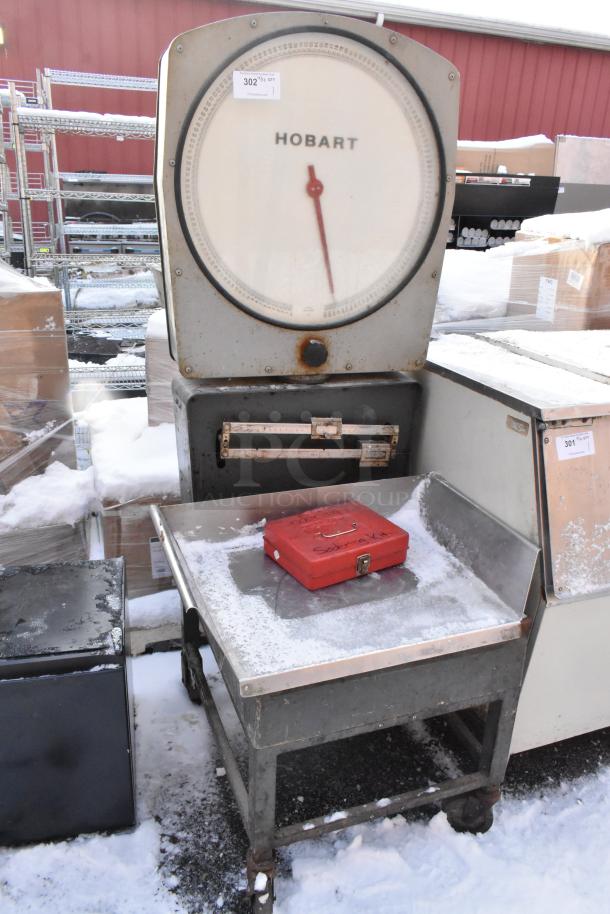 Hobart scale on metal stand with commercial casters, visible in used condition, outdoor setting with snow.