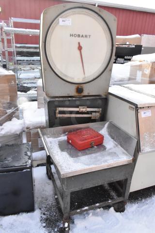 Hobart scale on metal stand with commercial casters, visible in used condition, outdoor setting with snow.