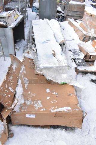 Four brand new scratch and dent items including a dunnage rack and work table covered in snow, visible cardboards, and partial wrapping.