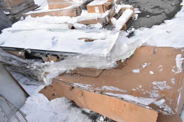 New scratch and dent items in snowy packaging, including a metal dunnage rack and a work table. Box slightly worn.