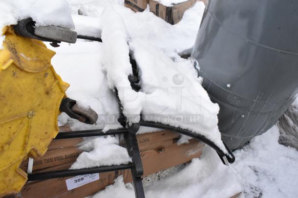 Pallet lot with various items including shortening shuttle, table bases, under snow, visible steel bases label.
