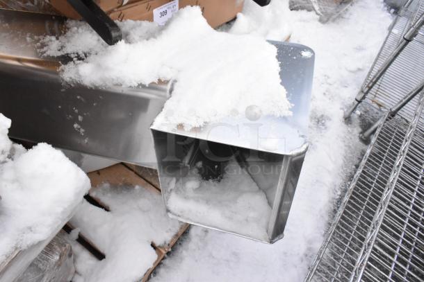 Pallet of various items, including a stainless steel shortening shuttle and table bases, covered in snow, brand new scratch and dent condition.