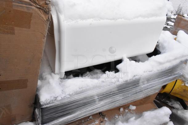 Pallet of various scratch and dent items, including tabletops and outdoor tables, partially covered in snow.