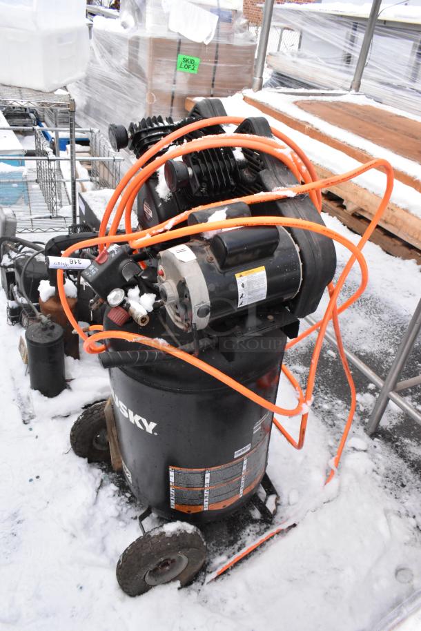 Husky C301H air compressor, in used condition. Black tank with visible orange hoses and labels.
