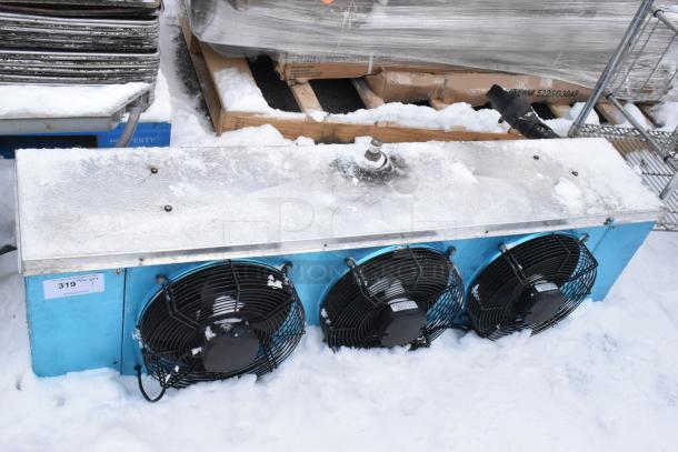 Metal commercial evaporator fan, 13,000 BTU, 220V, 1 phase, three fans, in snow. Seen with lot tag 319.