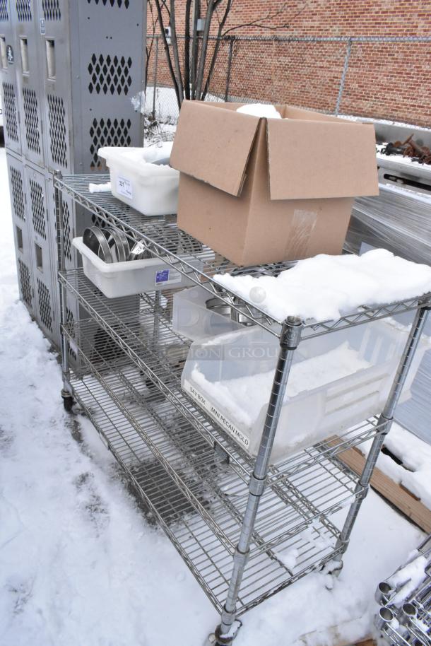 Chrome finish 4-tier wire shelving unit with various boxes and containers, snow-covered. Buyer must dismantle for removal.