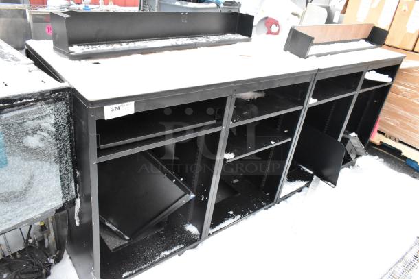 Two black metal counters with shelving, snow-covered surface, label indicates item 324, slight wear visible.