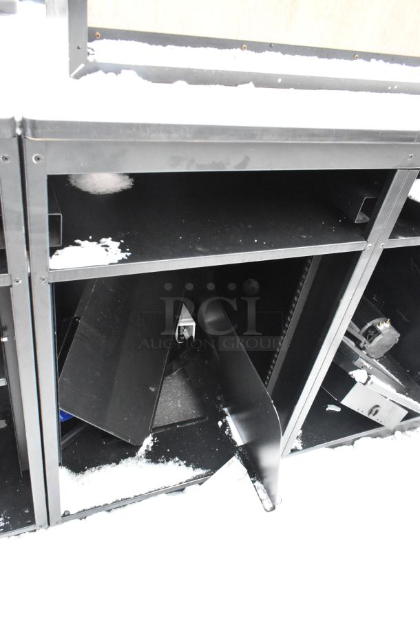 Two black metal counters, partially assembled, showing open shelves and snow cover, ideal for storage needs.