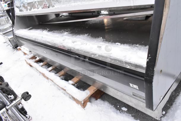 Commercial metal heated display case by Custom Deli's Equipment, floor style. Features visible wear, resting on wooden pallet.