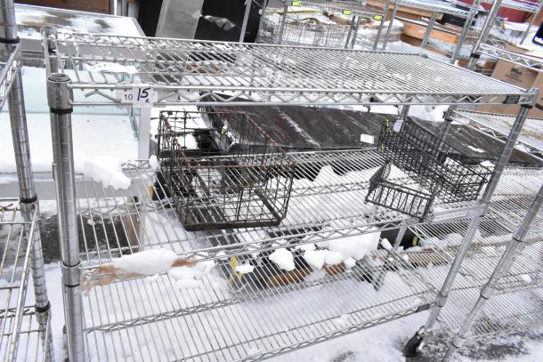 Chrome finish 3-tier wire shelf on commercial casters, outdoor setting, some snow accumulation, with attached storage baskets.