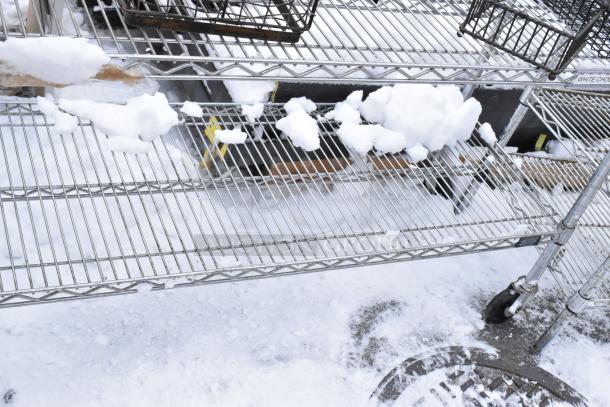 Chrome finish 3-tier wire shelf on commercial casters, snow-covered, requires buyer dismantling. Consider freight charges.