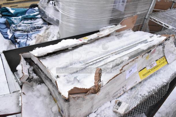 Heavy duty commercial shelving metal unit in damaged packaging, snow-covered, showing wear. Labels indicate item details.