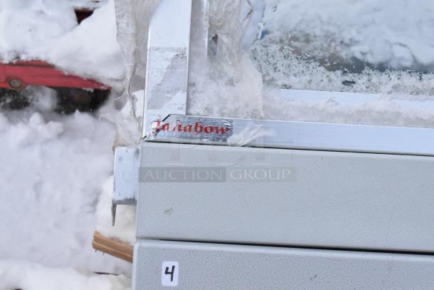 Gray metal display case merchandiser with a label, showing signs of wear and snow, marked with number "4".