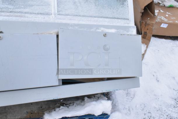 Gray metal display case merchandiser with hinged doors, showing light wear from exposure to snow and elements.