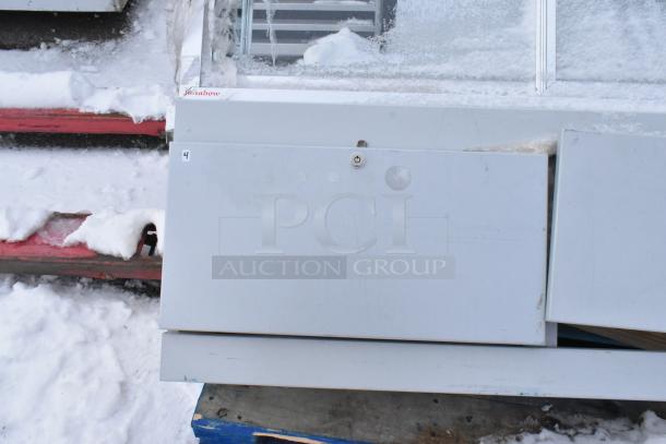 Gray metal display case merchandiser, featuring a lockable panel. Visible snow suggests outdoor storage. Marking: "Kolpak".