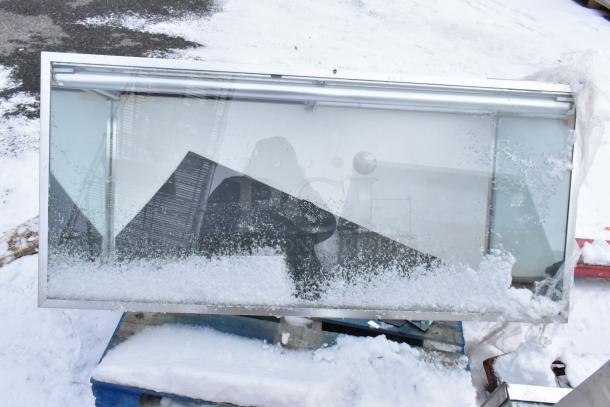 Gray Metal Display Case Merchandiser with glass front, showing signs of snow and frost, used condition.