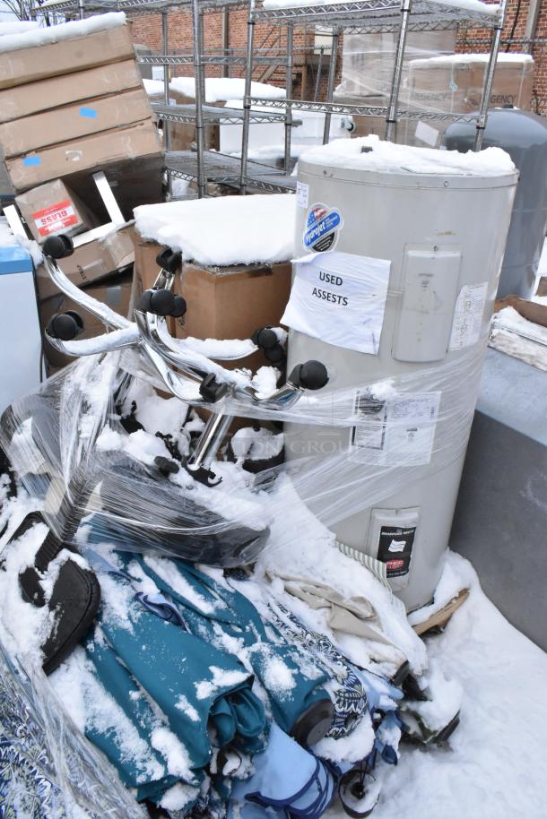 Pallet lot with Bradford White LD40S33B090 water heater, patio umbrellas, and boxed items, labeled "Used Assets," in snow.