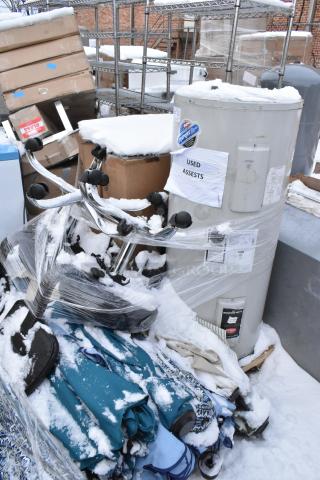 Pallet lot with Bradford White LD40S33B090 water heater, patio umbrellas, and boxed items, labeled "Used Assets," in snow.