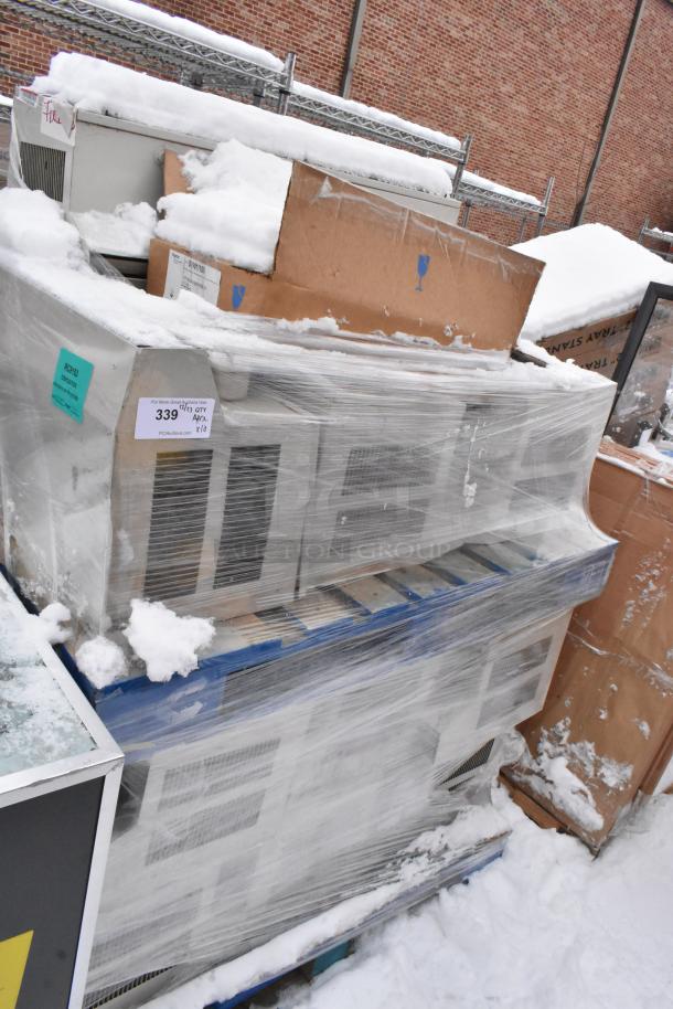 Pallet of 10 shrink-wrapped metal units and cardboard boxes with labels in snowy outdoor setting. Auction includes all.