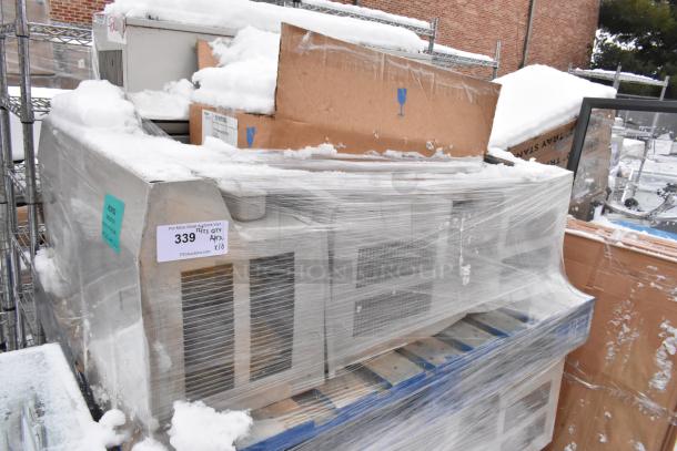 10 wrapped metal units covered in snow, stacked on a pallet. Auction label reads "339, Qty Approx. x/10."