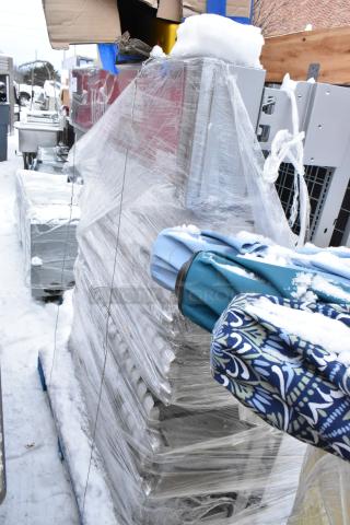 Stacked metal pieces wrapped in plastic with snow on top, accompanied by patterned fabric items, suggesting mixed lot sale.