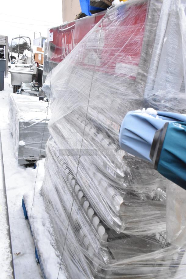 Plastic-wrapped pallet with gray metal pieces on snow. Auction includes three items; unclear labels. Condition appears used.