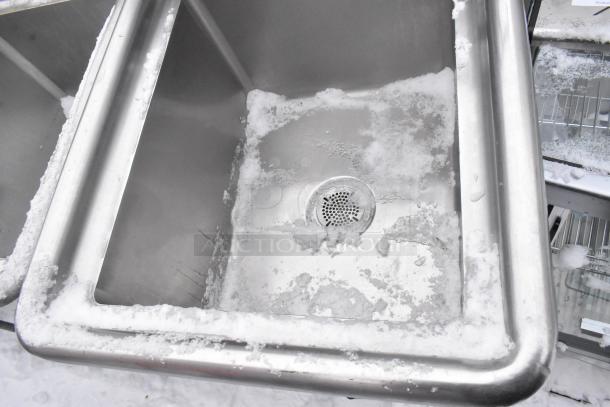Stainless steel single bay sink with visible faucet and handles, showing ice buildup around the edges.