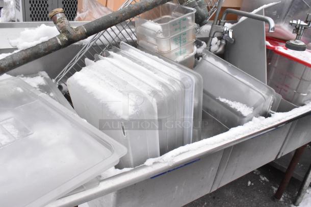 Stainless steel 3 bay sink with left side drain board, includes poly bins, some snow-covered. Ideal for commercial use.