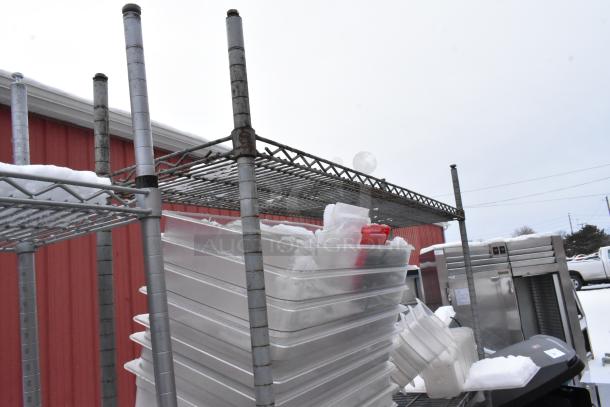 Chrome finish 4-tier wire shelving unit with poly bins. Buyer must dismantle. Snow visible on shelves.