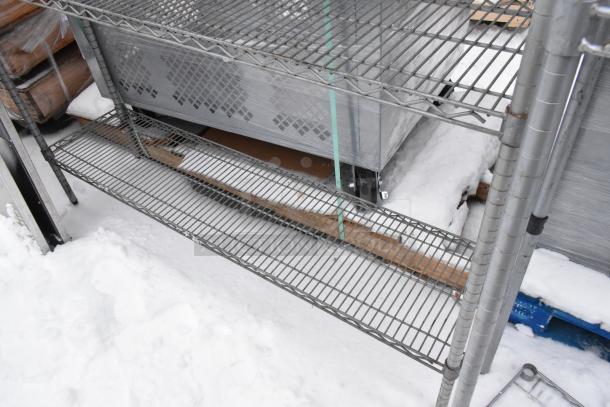 Chrome finish 4-tier wire shelving unit with contents including a sink, outdoors in snow, requires dismantling.