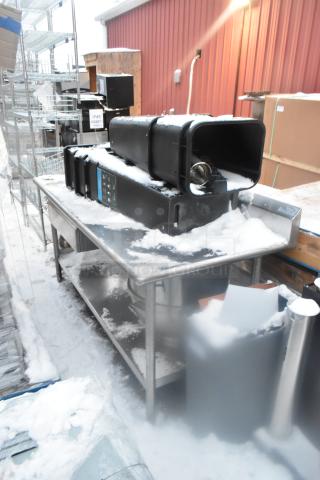 Stainless steel table with under shelf, snow-covered surface, includes poly trash cans. Outdoor setting. Used condition.