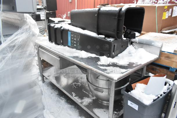 Stainless steel table with under shelf, includes various contents and poly trash cans, lightly snow-covered.