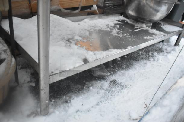 Stainless steel table with under shelf, some snow on surface, includes poly trash cans, used condition.