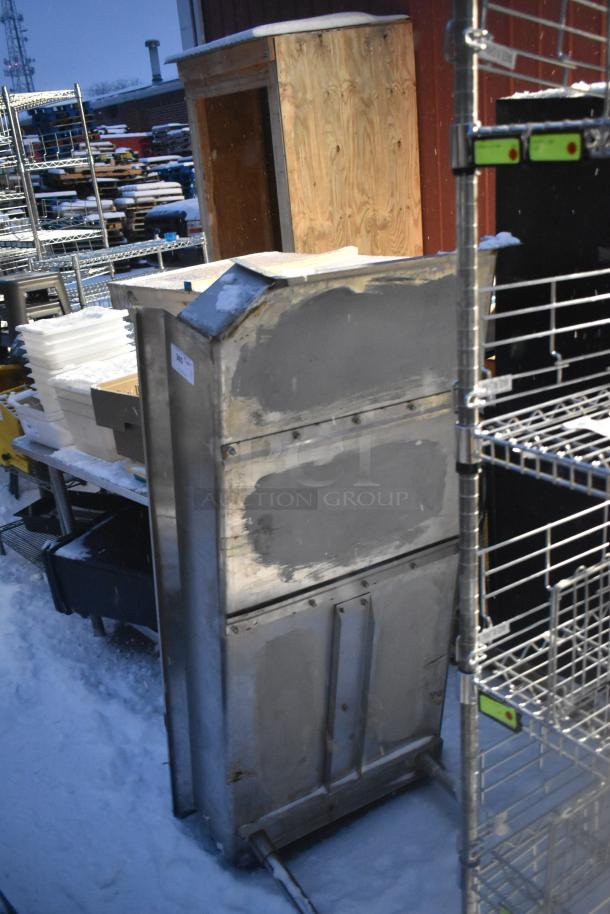 Stainless steel clean side dishwasher table, used condition, visible surface wear and patches, outdoors in snowy setting.