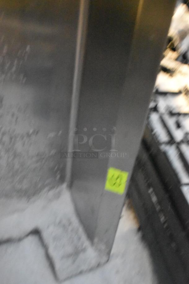 Stainless steel dishwasher table, featuring a clean side design. Shows some wear; yellow tag attached.