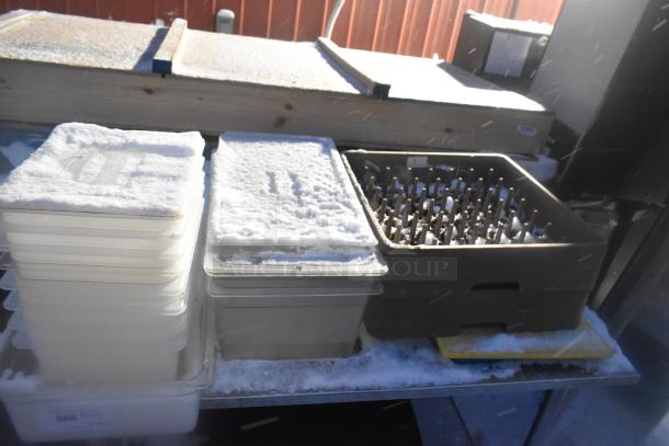Stainless steel table with under shelf holding poly bins, trash can, and glass racks, covered in snow.