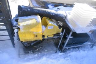 Chrome 2-tier wire shelving unit with mop bucket. Snow-covered. Buyer to dismantle. Includes freight considerations.