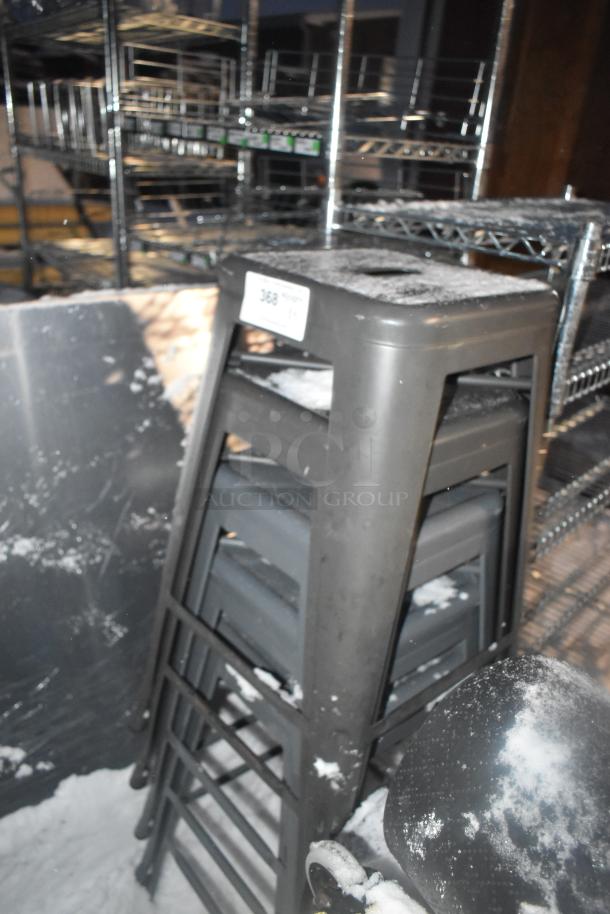 5 gray metal Tolix-style stools, stackable, in used condition, showing some light wear. Auction label visible on top stool.
