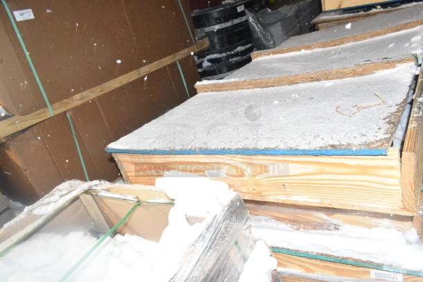 Three brand new items in crates, unopened and sealed. Tag shows item number for tracking. Snow visible on crates.